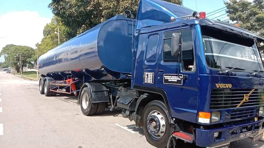 Blue Volvo prime mover with liquid tanker on the road